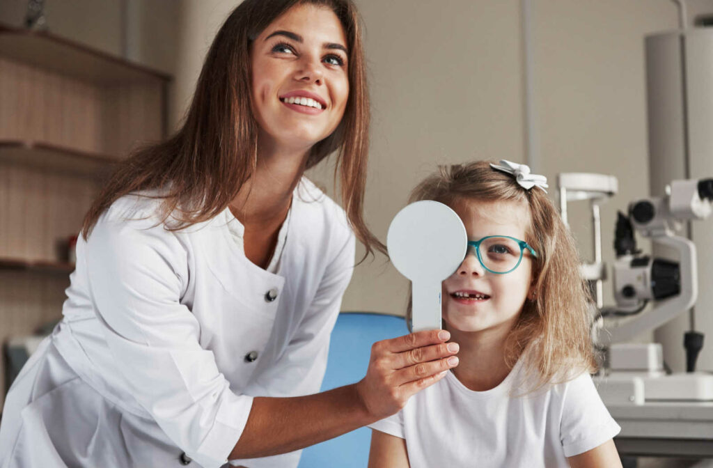 A young child wearing glasses with strabismus having their eyes examined during an eye exam.