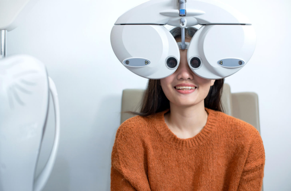 A woman sitting in an optometrist's office looking into a machine that tests her vision.