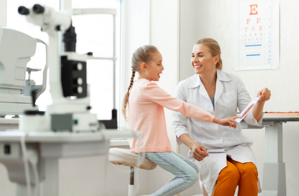 An optometrist showing an cross-section of an eye to a young girl during her eye exam.