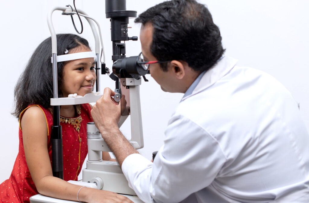 An eye doctor examining a young girl's eyes during a pediatric eye exam.