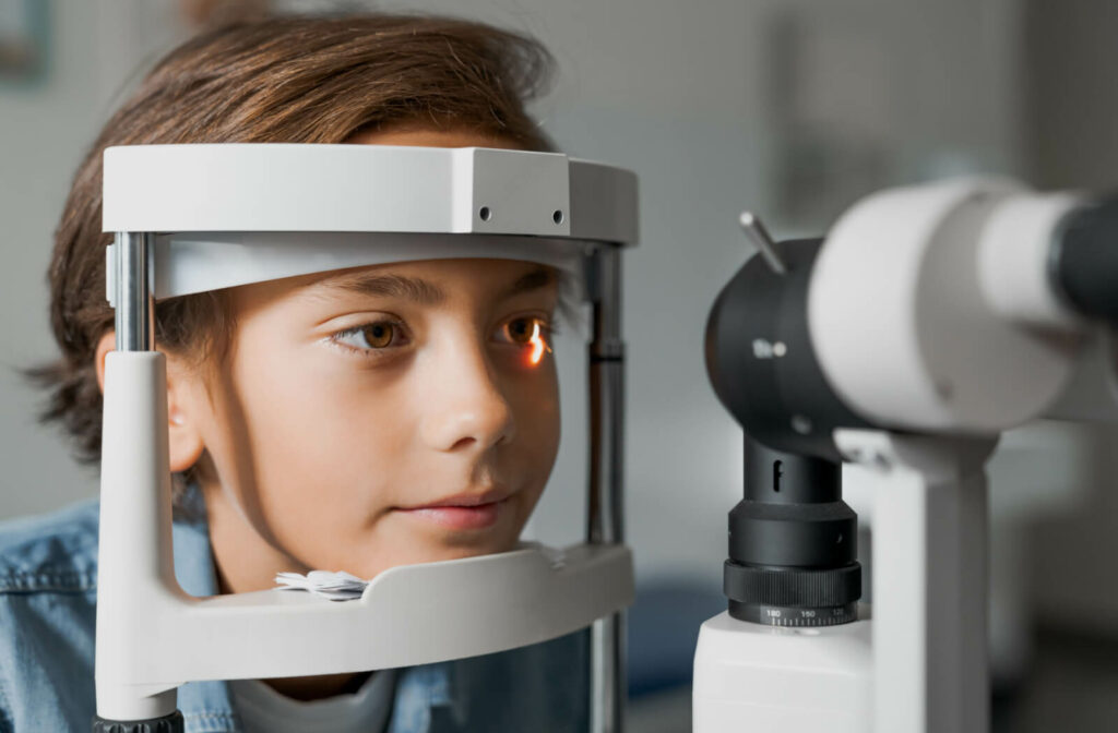A child sitting in an optometrist office looking into a machine that tests his vision.