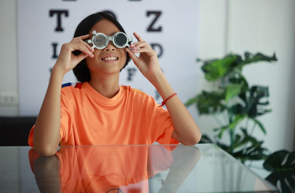 Young girl smiling while trying on trial frames for progressive myopia correction during an eye exam.