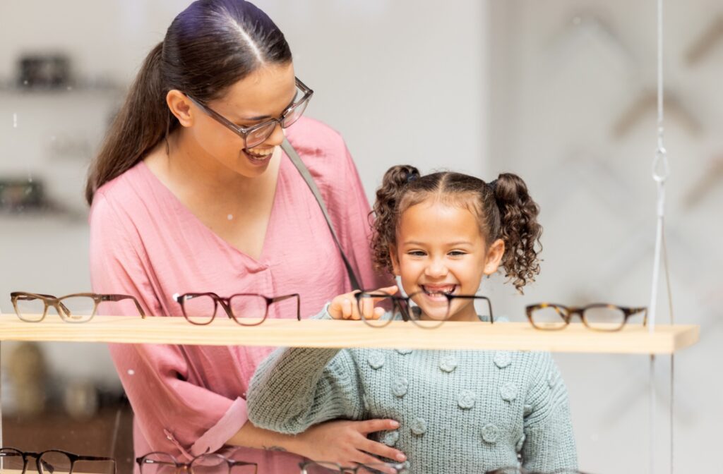 A parent helps their child pick out their first pair of glasses.