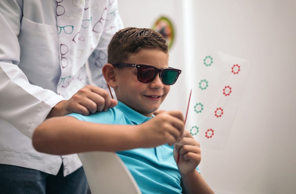 A child at their eye doctor working on a vision therapy exercise using red and green tinted glasses to work on convergence-divergence.