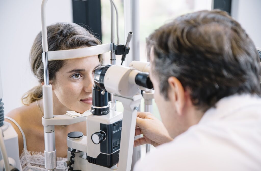 A person looks into a slit lamp while an eye doctor conducts an eye exam.